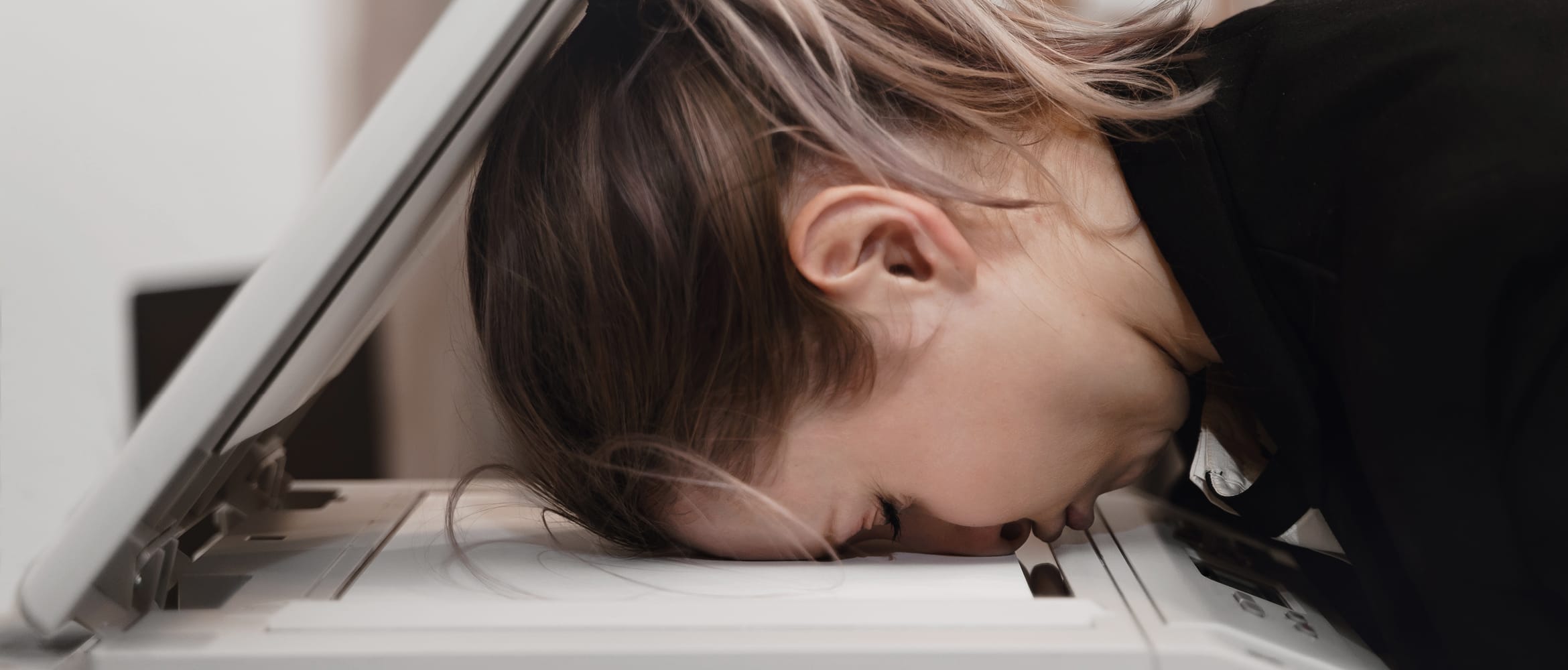 A business woman with her head face down in a photocopier