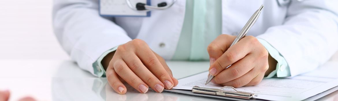 Close-up of a female doctor writing patient notes on a clipboard