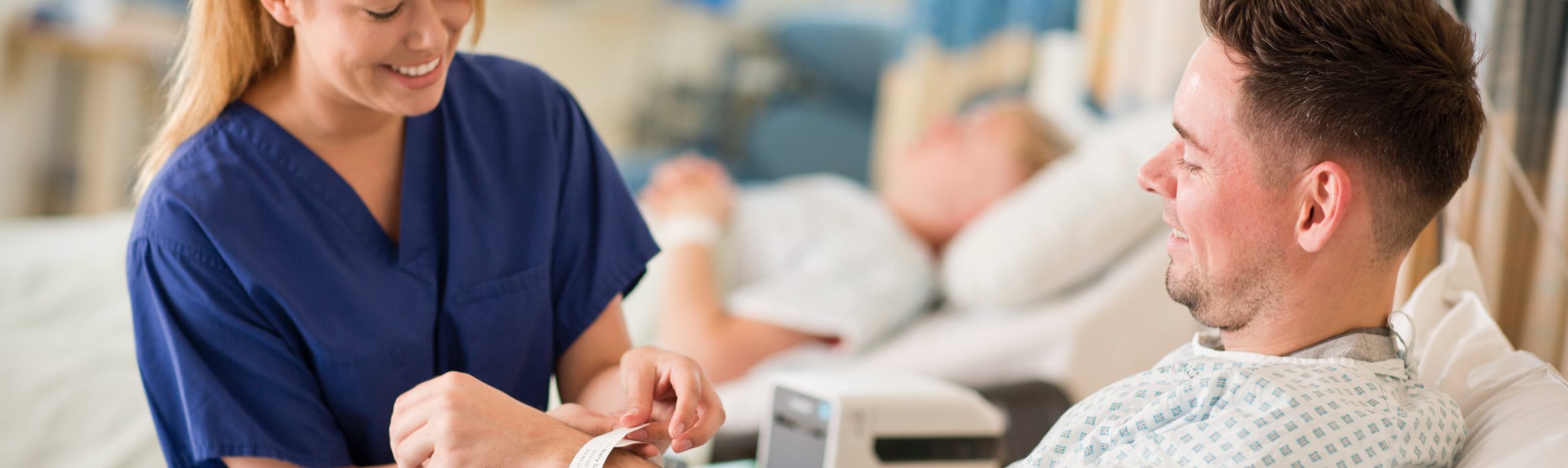 A healthcare professional attaches an identification wristband to a patient in a hospital ward