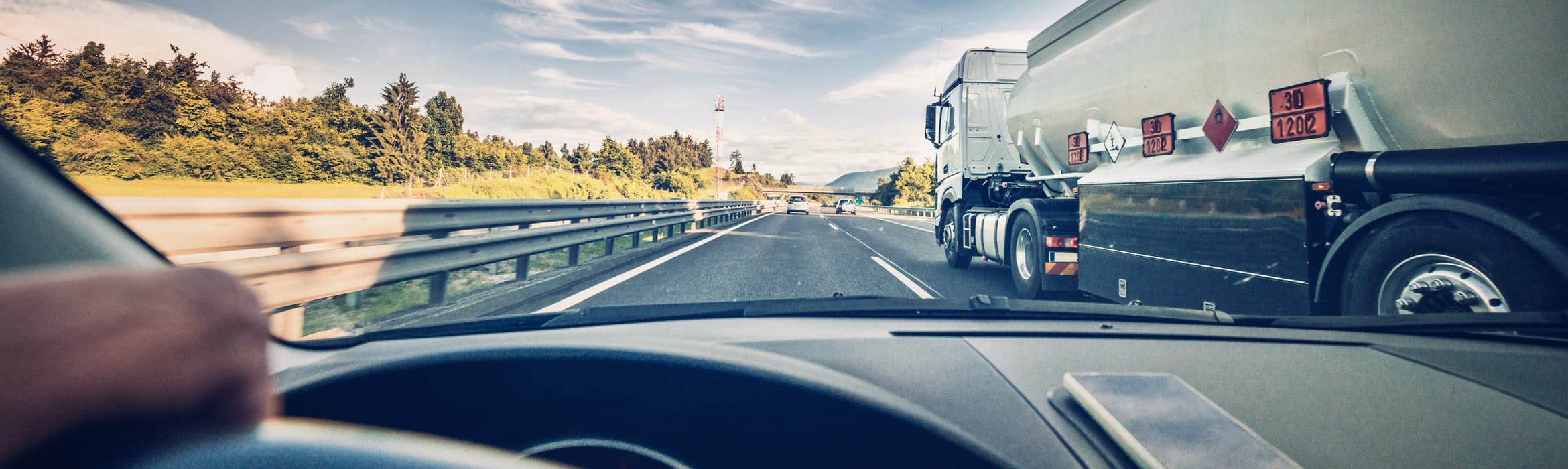 View from a drivers perspective in a car travelling along a motorway with a white heavy goods vehicle passing on the right-hand side