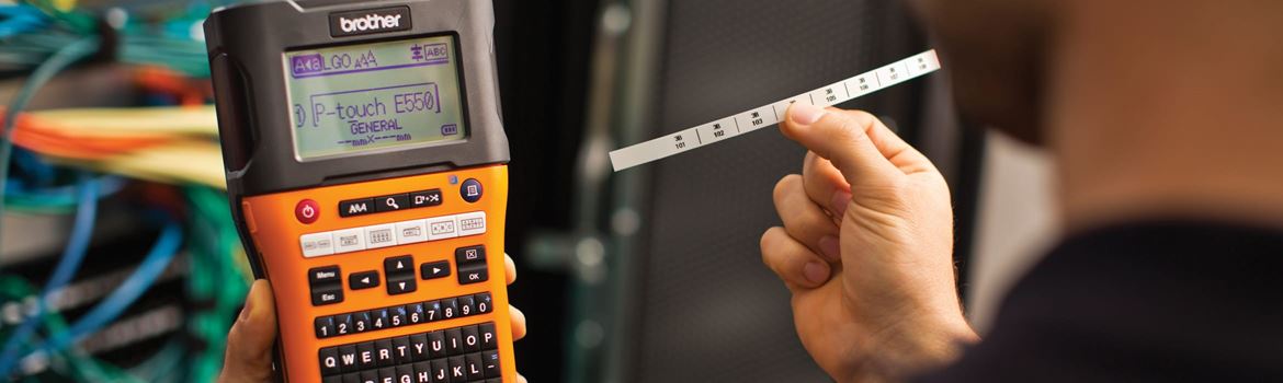 An electrician using a Brother PT-E550 handheld label printer to print electrical cable labels