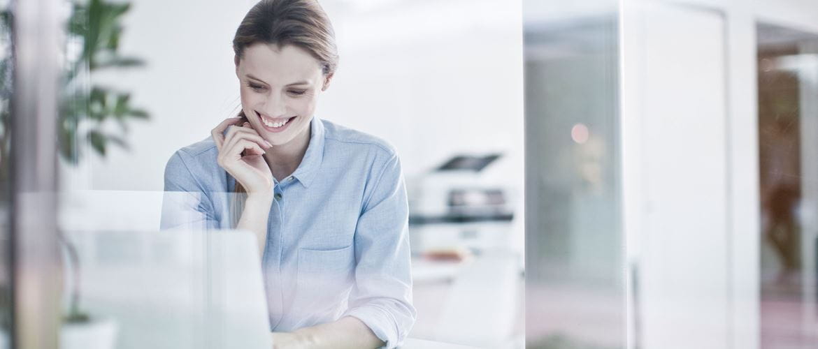 Business woman looking down at laptop while smiling