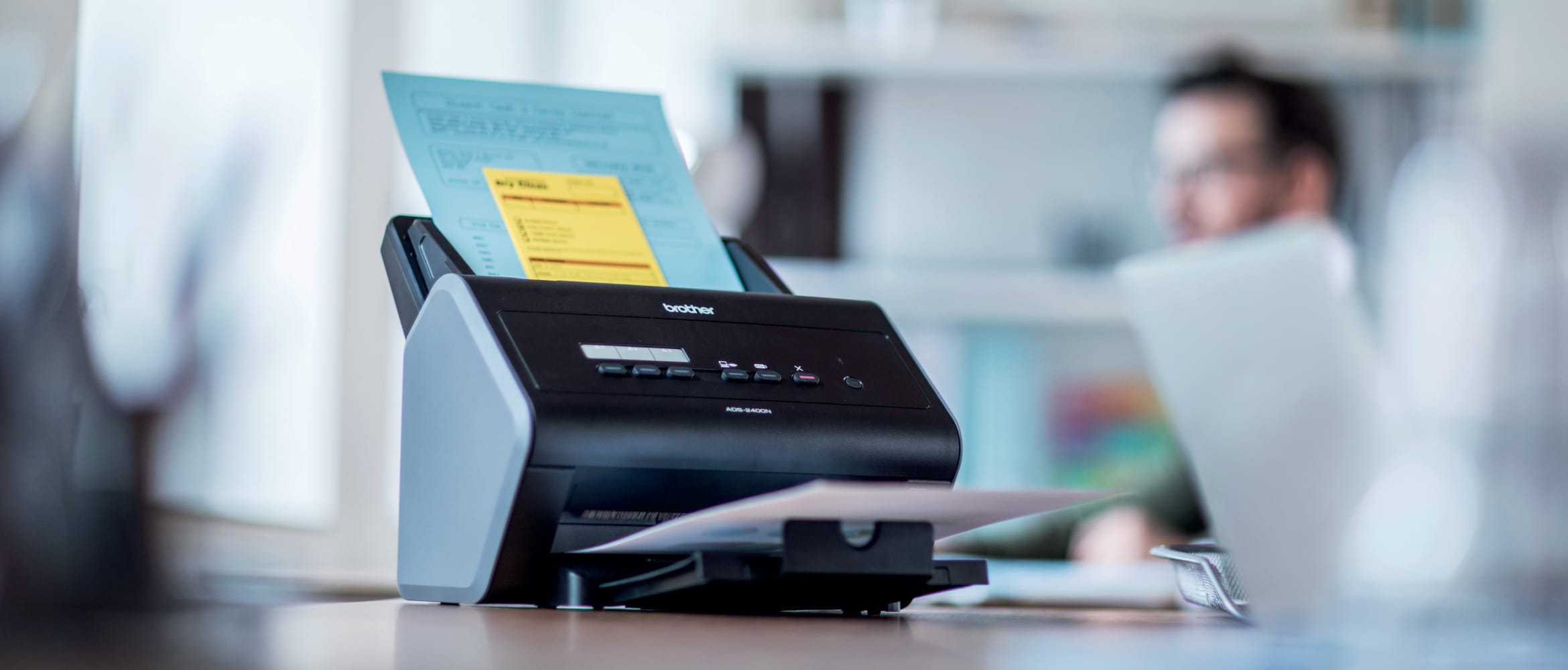 Brother ADS-2400 multiple page scanner on a desk in an office environment