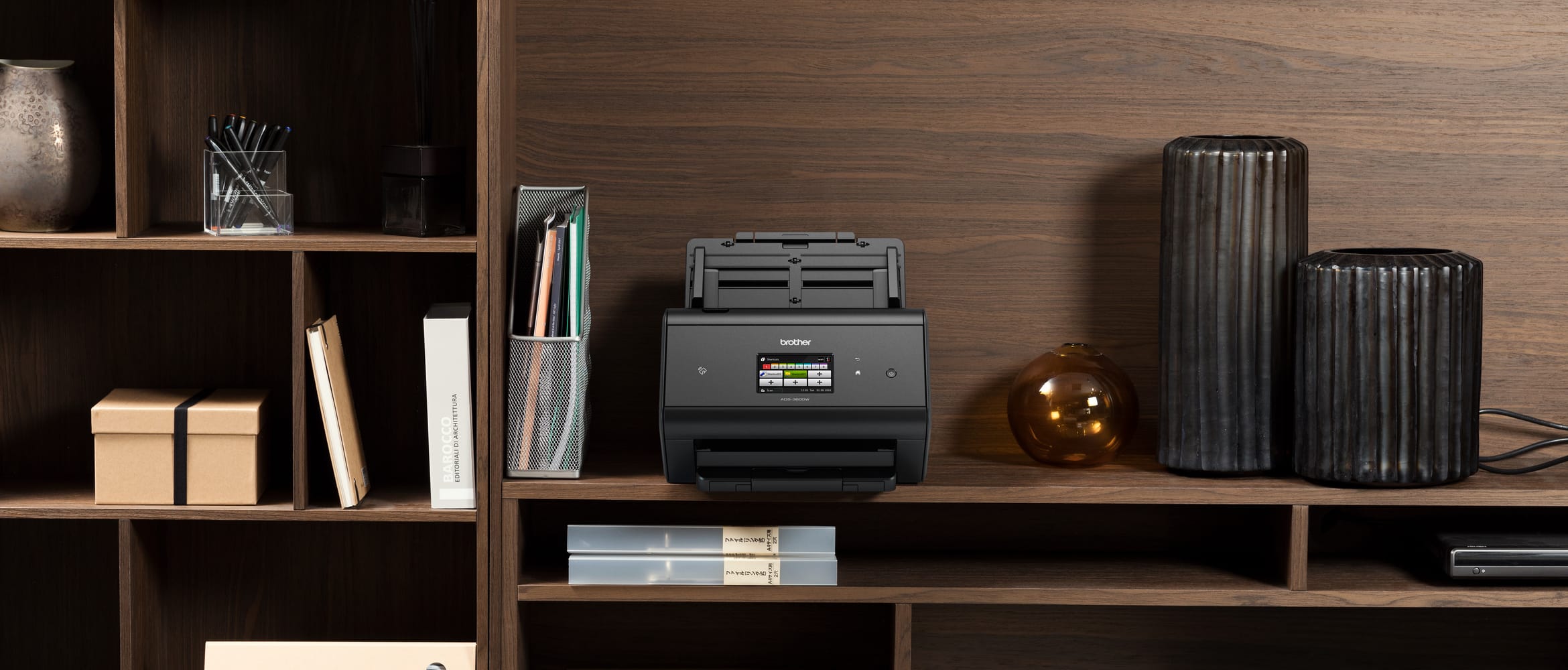 Brother ADS-3600W secure scanner on a dark wood shelving unit with a mixture of office and decorative items