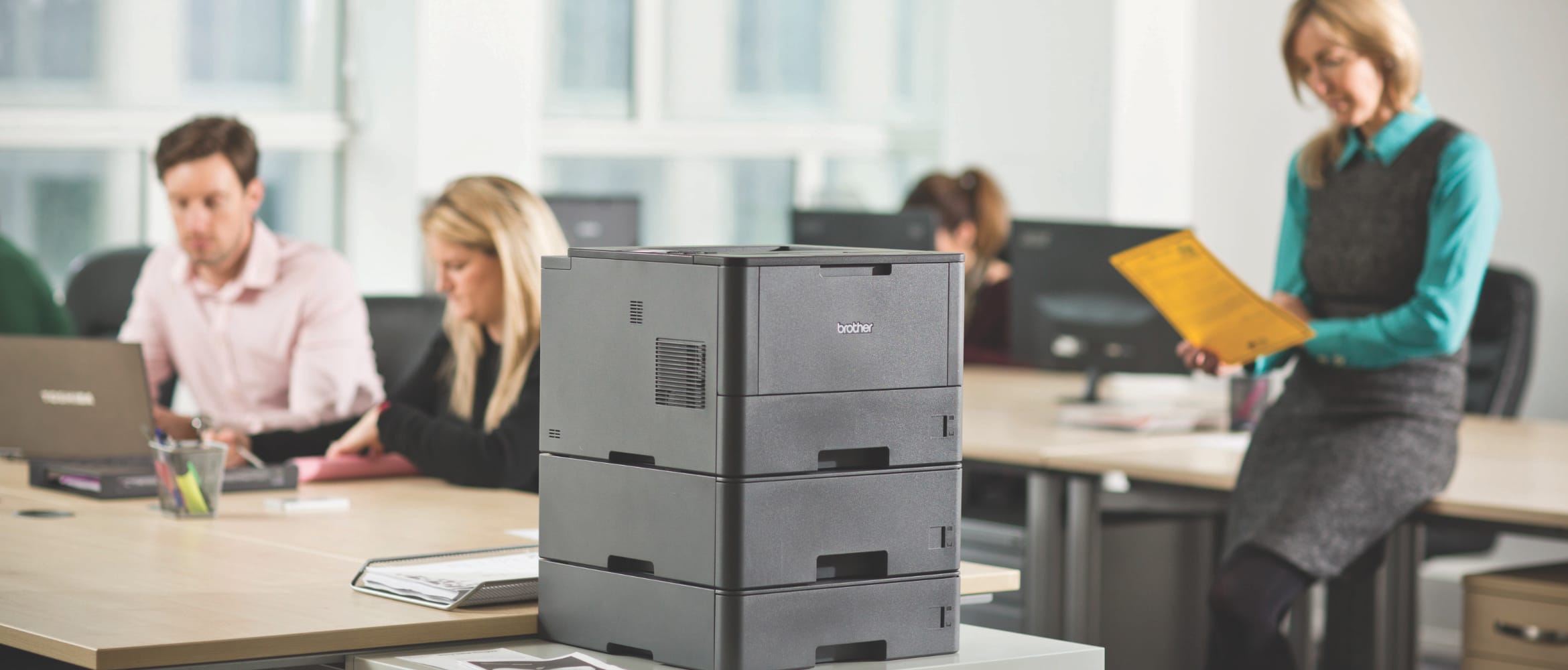 Brother HL-L5100DN workgroup mono laser printer on a table in a busy office environment
