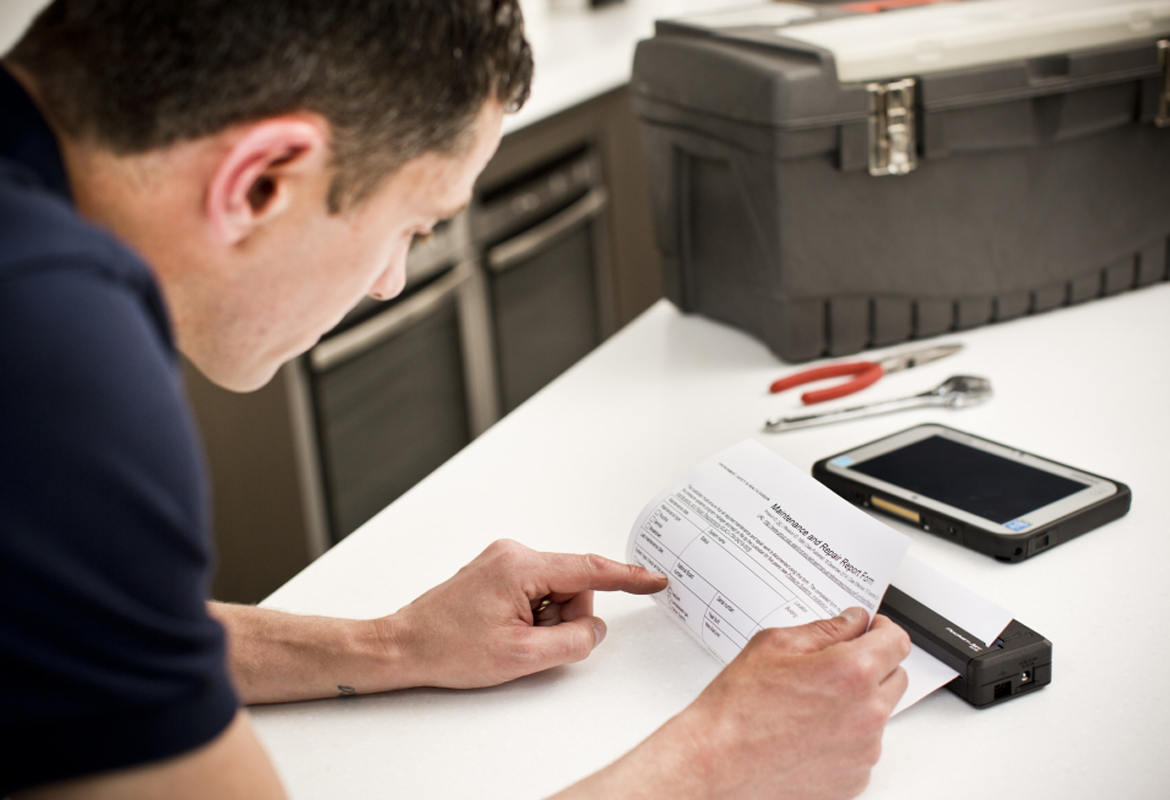 A field service engineer reviewing a printout from a mobile printer