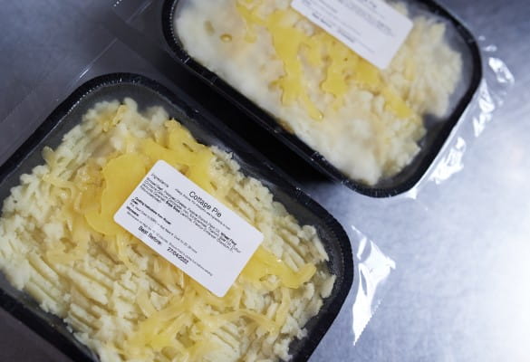 Two cottage pies in plastic wrapping with Brother printed labels listing out ingredients, cooking instructions and best before dates 