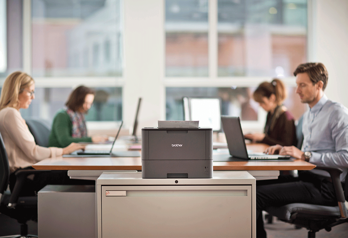 Brother laser printer sat on desk with staff sat behind