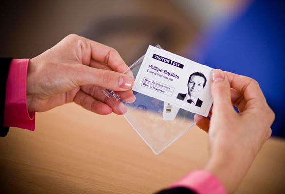 A woman inserting a visitor ID card into a clear plastic lanyard