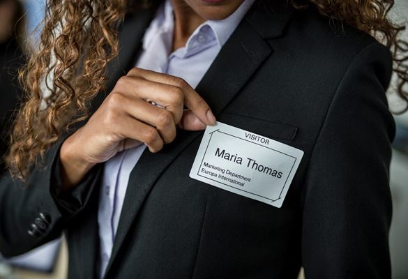 Close-up of a business woman affixing a visitor name badge to her jacket