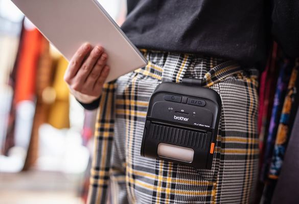 A retail sales assistant holding a tablet device with a Brother RJ Series label printer clipped onto her belt