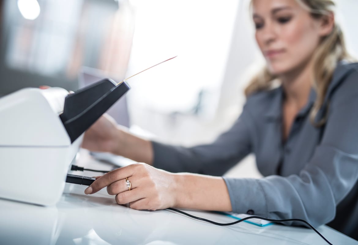 A business woman inserting a USB flash drive into the rear of a Brother ADS-2700 multiple page scanner