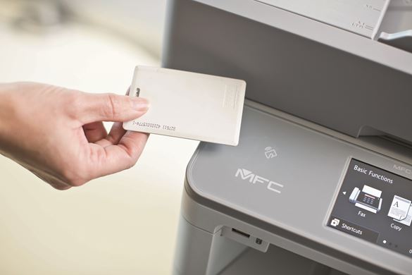A hand holding a card over a Brother printer with a MFC card reader 