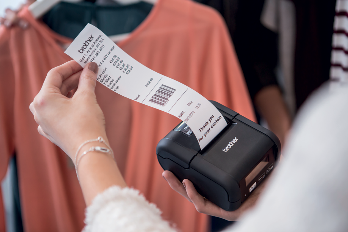 A sales assistant removing a receipt from a mobile printer in a retail environment