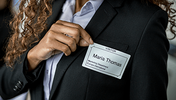 Podnikatelka lepí štítek návštěvníka na své sako