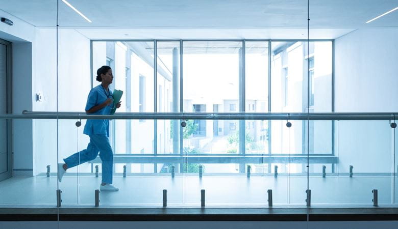 Female surgeon carrying medical reports running along a corridor in a hospital