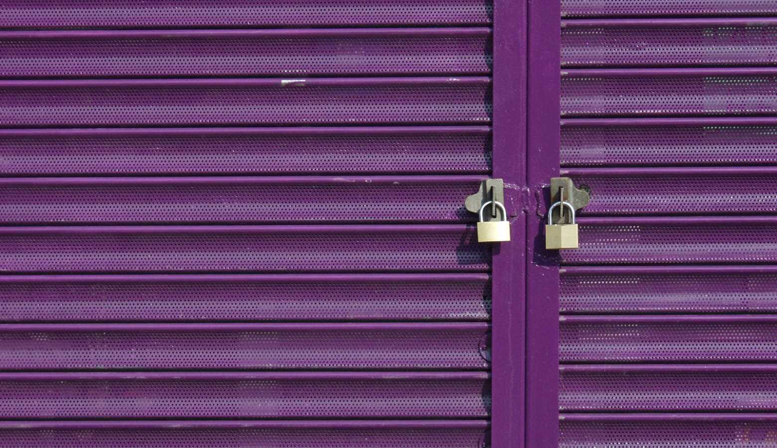 Two padlocks on purple retail store shutters