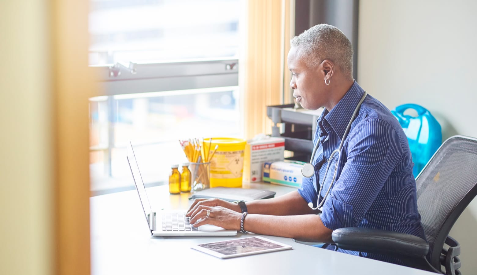 Female doctor typing on a notebook computer while sitting at her desk