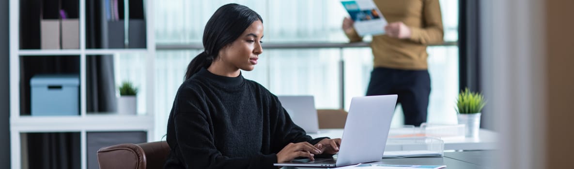Female wearing a red top sat at a desk working on a computer around stationary with a Brother printer on the desk