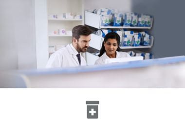 Male and Female pharmacists behind counter in pharmacy