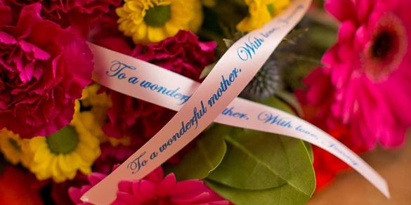 A pink personalised ribbon on a bouquet of flowers created on the Brother Tape Creator