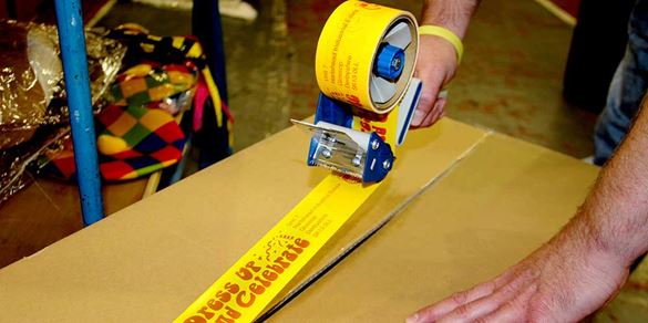 A warehouse worker seals a box shut with customised packing tape created on the Brother Tape Creator Pro