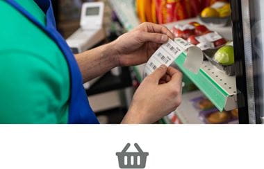 A supermarket worker adding a shelf edge label