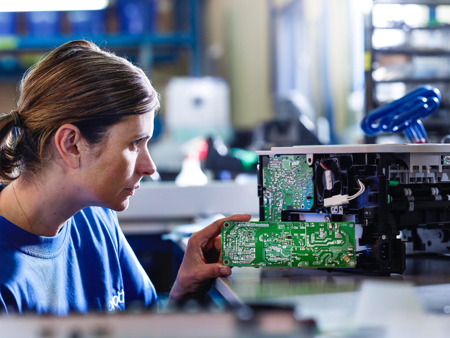 A technician dismantling an old printer in a workshop environment