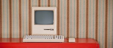Old retro computer on a red table with dated wallpaper