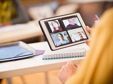 Woman using a tablet device to video conference with four people