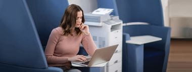 Woman sat next to MFC-L6900DW mono laser multifunction printer in an office 