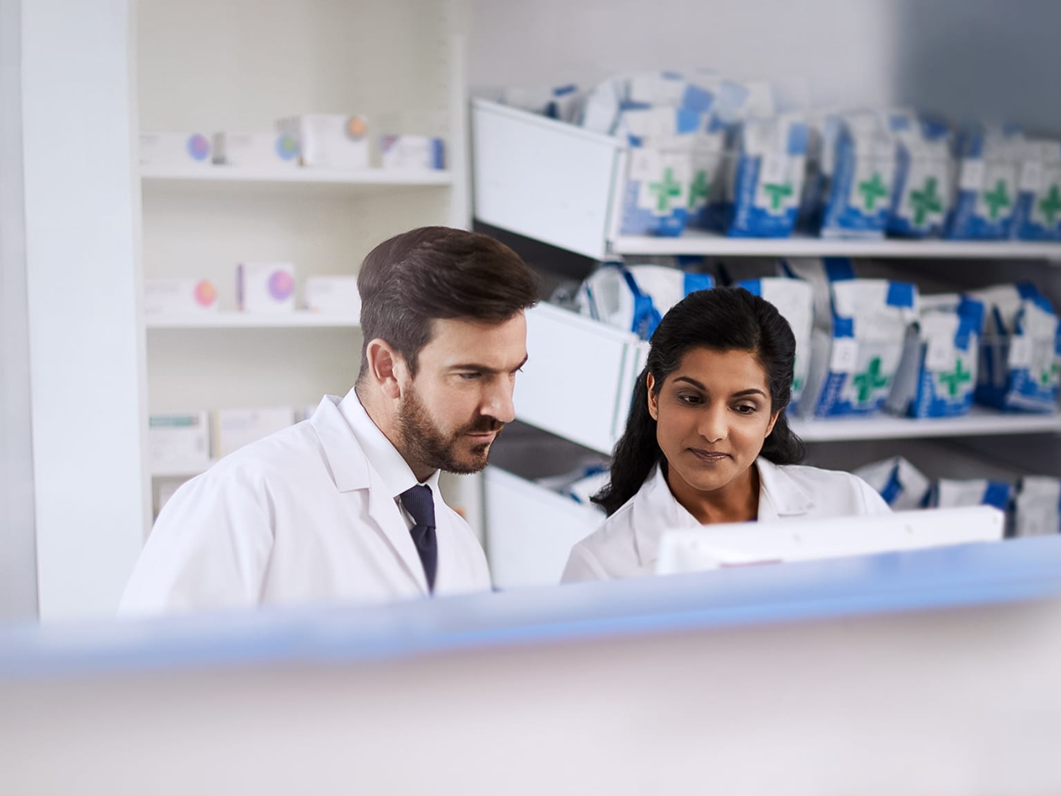 Male and Female pharmacists behind counter in pharmacy