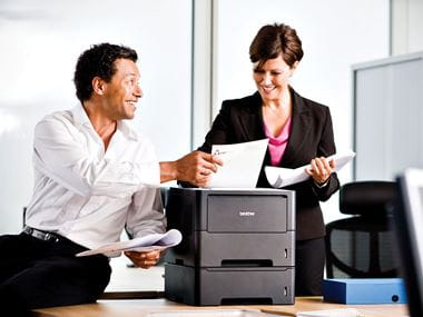 man and woman discussing business over a Brother printer