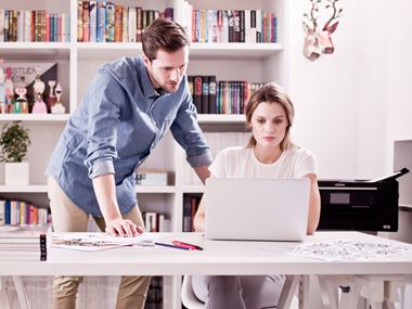 Man standing next to a lady on her computer
