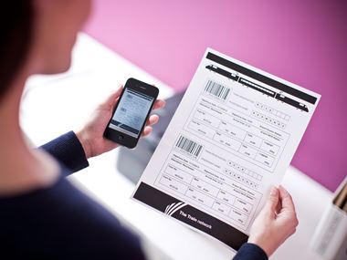 person holding up their phone next to a document 