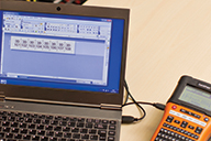 Brother PT-E550WNIVP label printer connected to a PC running P-touch Editor label design software using a USB cabl