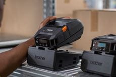 Brother RJ-3200 rugged printer being picked up from charging cradle in warehouse