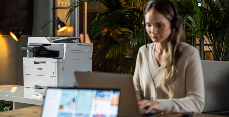 A woman using a laptop computer while sat at a desk in an SMB environment