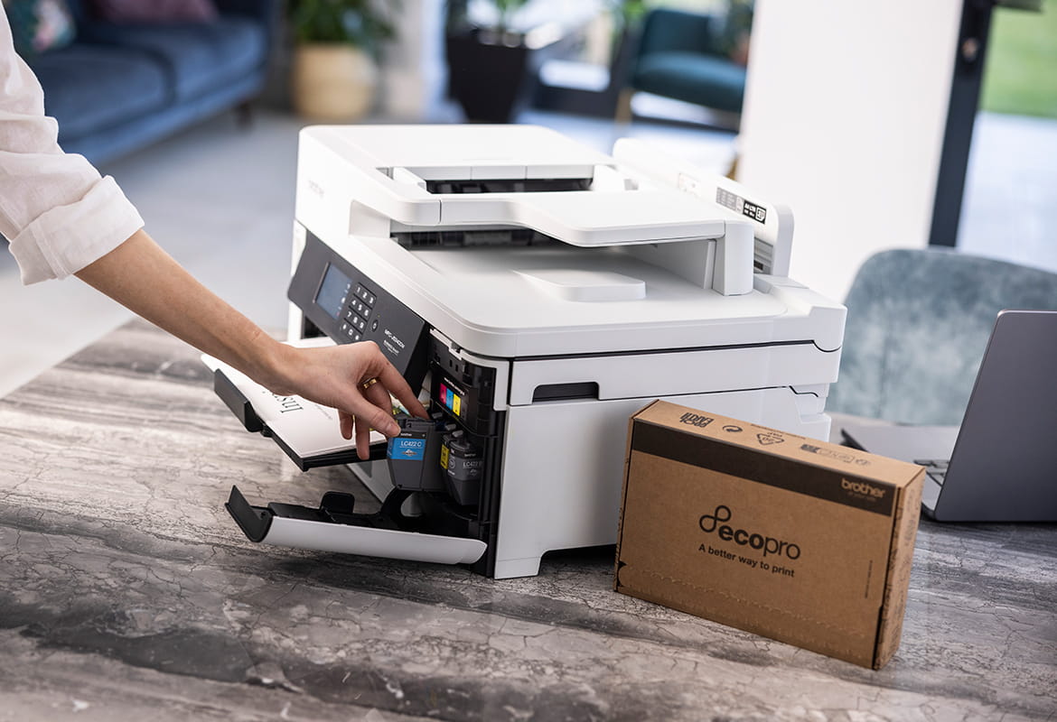 Woman placing ink cartridge into printer on a table with an EcoPro box next to it