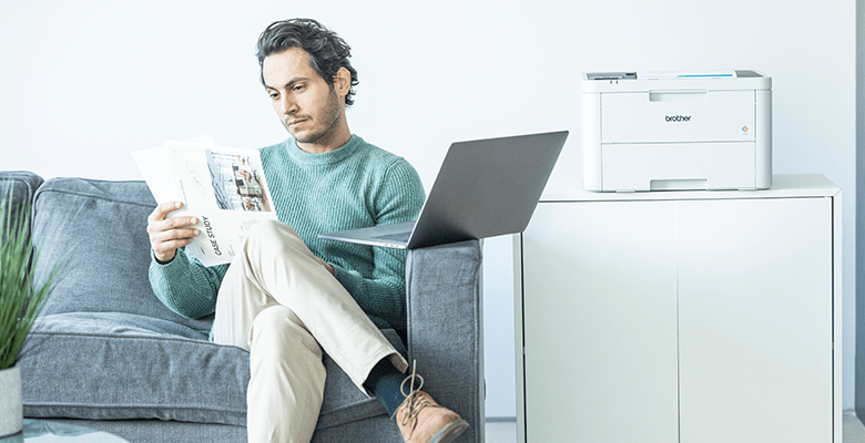 A man reading a document while sat on a sofa in an SMB environment
