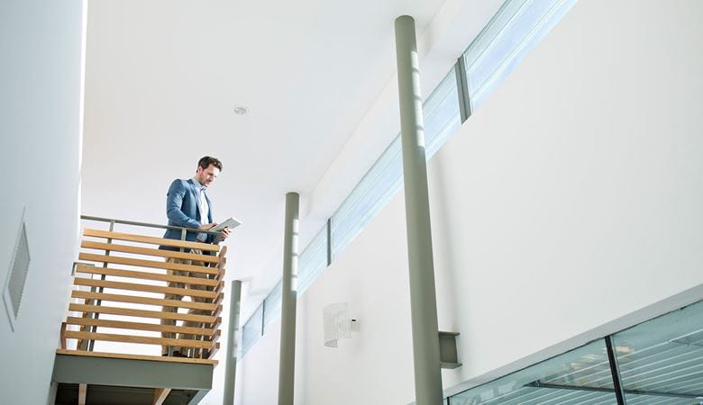 Businessman looking at tablet device while standing on balcony in office environment