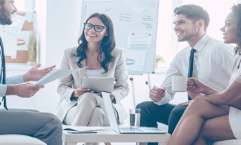 Four colleagues in an office meeting having discussion around coffee table