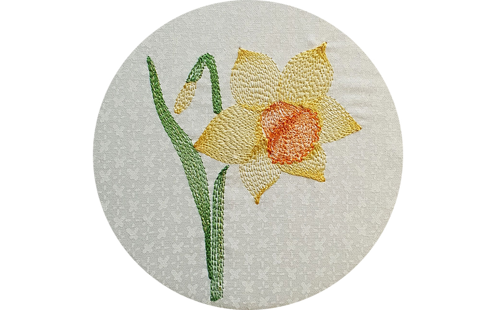 Embroidered yellow daffodil on white fabric.