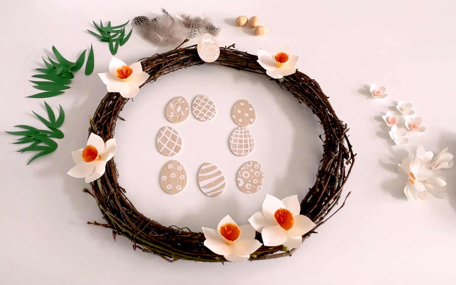 wooden wreath surrounded by papercraft flowers and balsa eggs