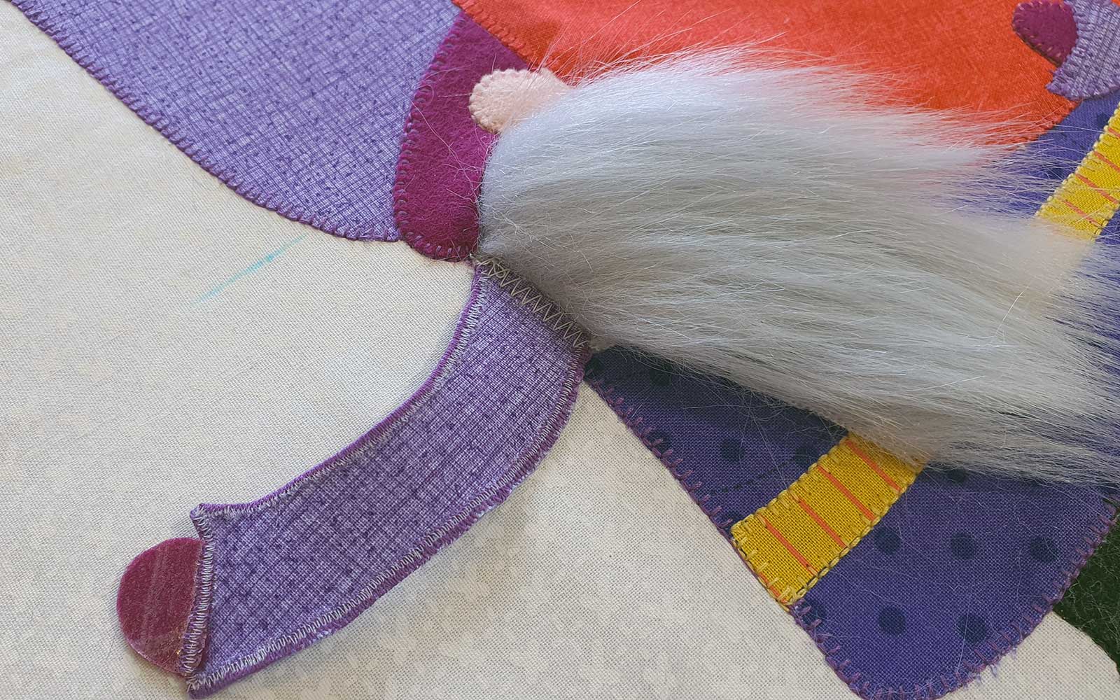 Purple arm of gnome on white fabric