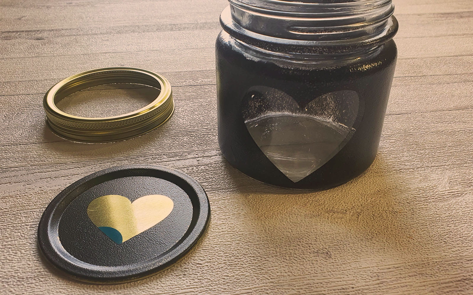 jar painted black with heart shaped peephole and lid next to it