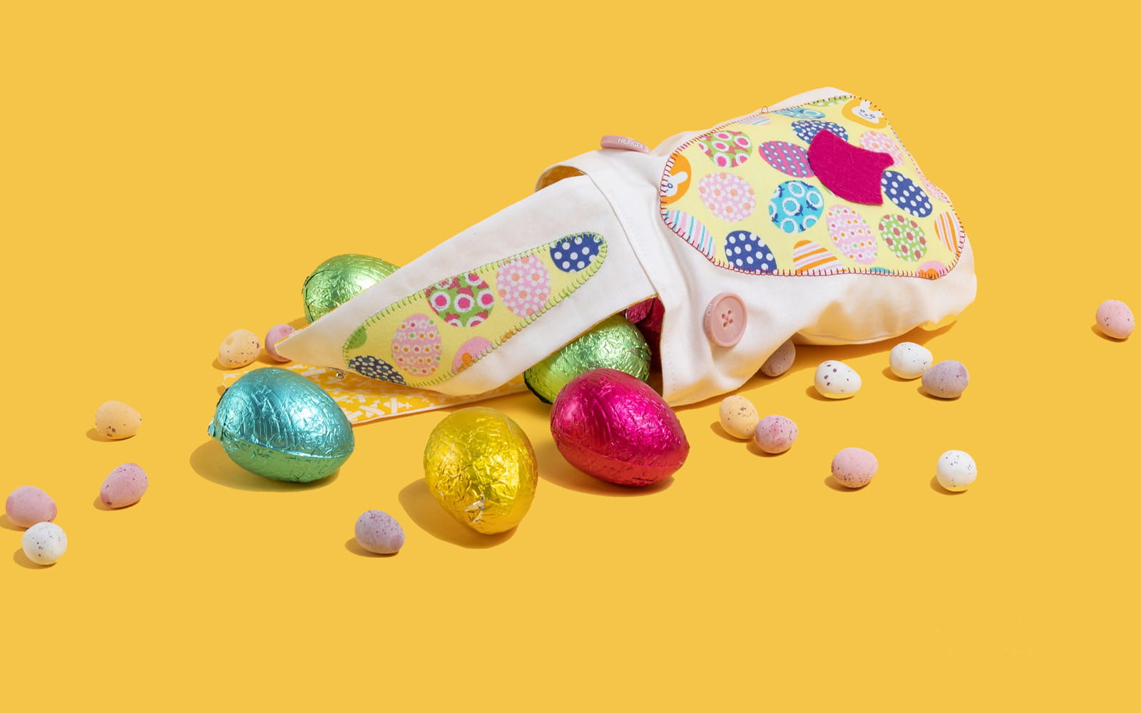 Easter bunny bag with chocolate eggs on yellow background