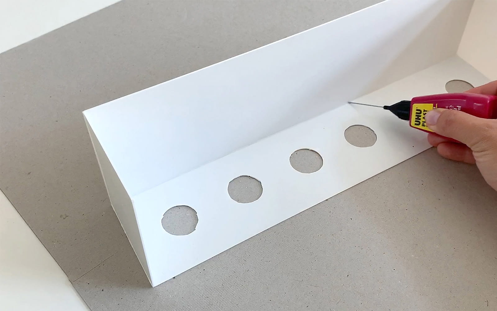 hand tracing glue inside white polystyrene 3D L shape
