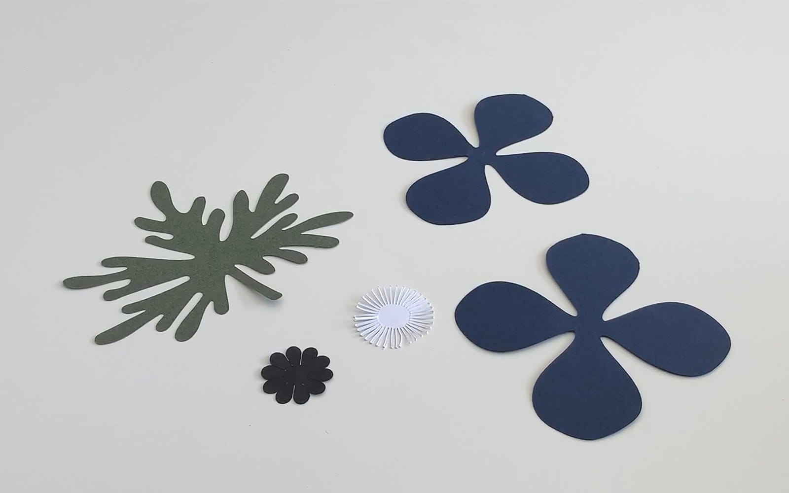 Blue and white paper flower pieces flat lay white background