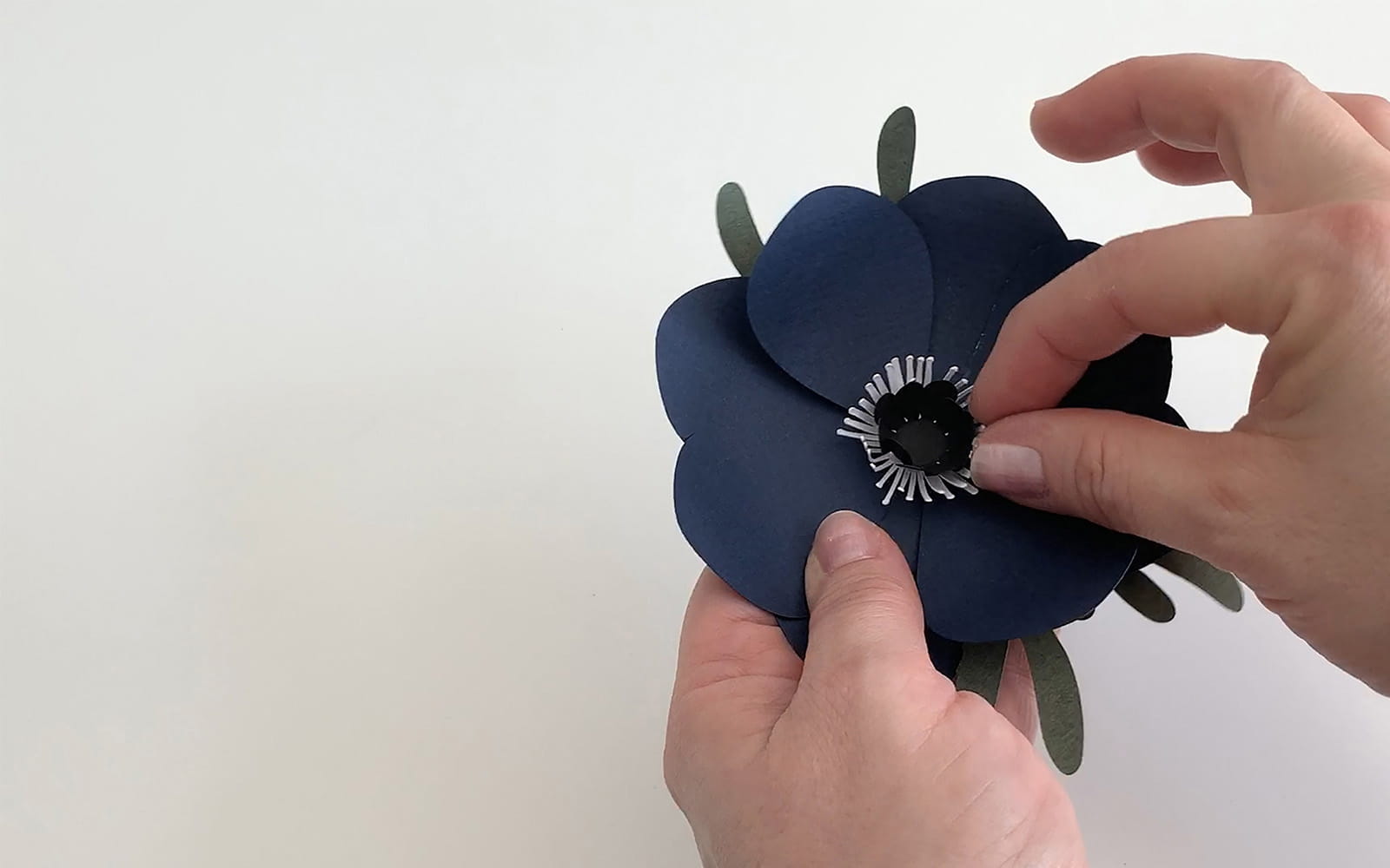 A hand holding a blue cut paper flower